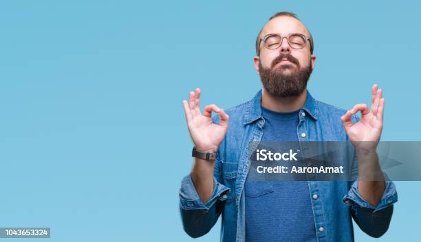 Young Caucasian Hipster Man Wearing Glasses Over Isolated Background Relax And Smiling With Eyes Closed Doing Meditation Gesture With Fingers Yoga Concept Stock Photo - Download Image Now