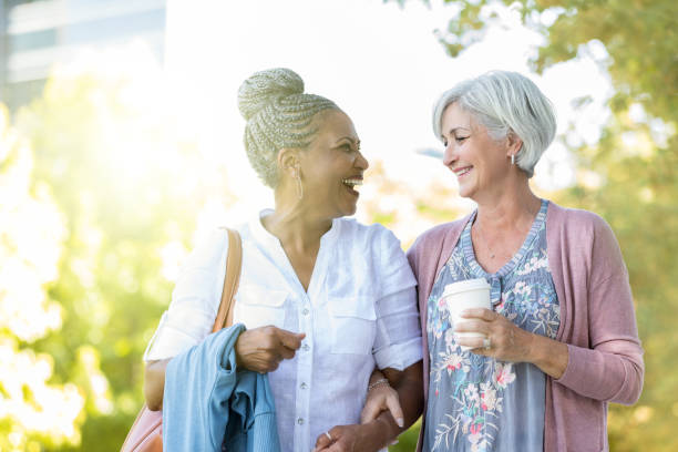 two senior women walk outdoors together - adult senior adult black white imagens e fotografias de stock