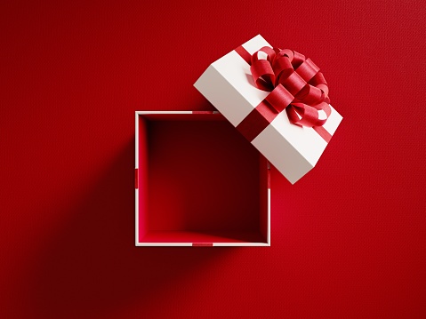 Open white gift box tied with red ribbon on red background. Horizontal composition with copy space. Directly above. Great use for Christmas and Valentine's Day related gift concepts.