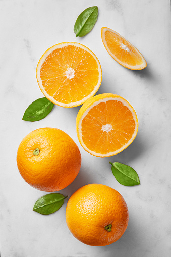 Orange selection isolated on a marble background viewed from above. Fresh citrus fruits arranged, cut and whole. Top view