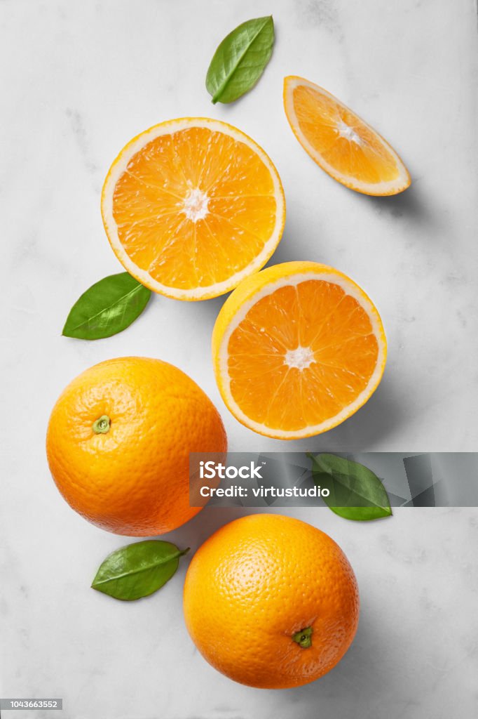 Orange selection isolated on a marble background viewed from above. Fresh citrus fruits arranged, cut and whole. Top view Orange - Fruit Stock Photo