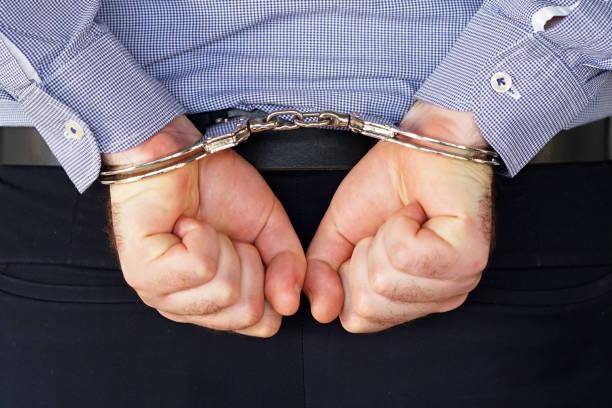 istock Criminal hands locked in handcuffs. Close-up view 1043663676
