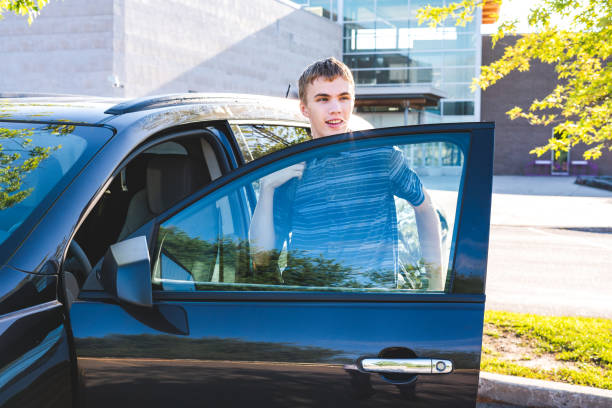 Teenager stepping out of his car on the first day of school. stock photo