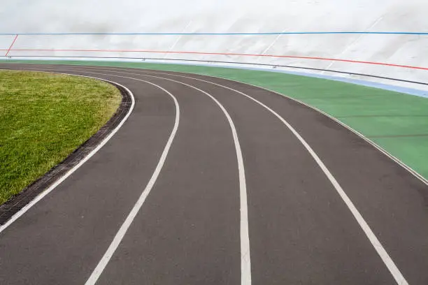 Track and field concept. High angle top view cropped photo of new modern public bicycle track or racetrack with green lawn on the open air for speed run on color market asphalt road