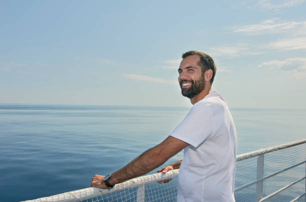 istock Handsome man smiling on the deck of a ship during holidays. 1043678018