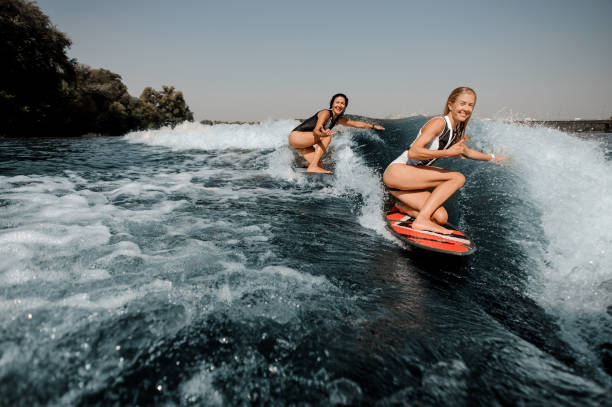 istock Two women wakesurfing on boards down the blue wave 1043681558