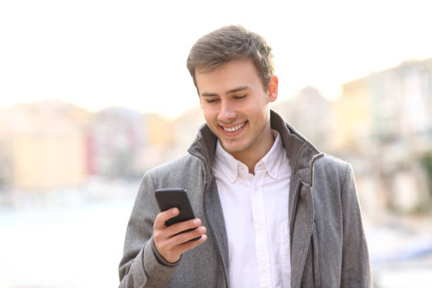 istock Man using a smart phone in winter walking in a coast town 1043685186