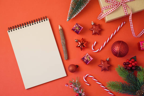 istock Christmas holiday background with notebook and decorations on red table. Top view from above 1043689522