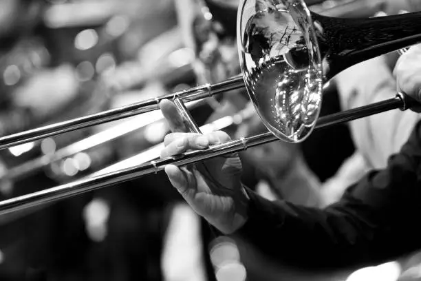 Trombone in the hands of a musician close-up in black and white tones