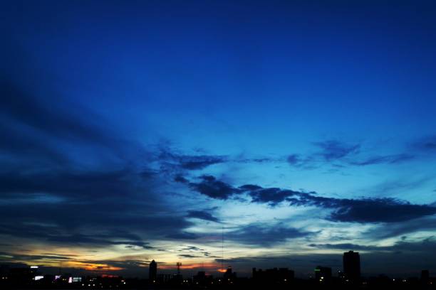 Photo of night sky with thin layer of cloud during blue hour. Twilight dusk sky over city scene. calmness over bustling city. silhouette city under colorful atmosphere.