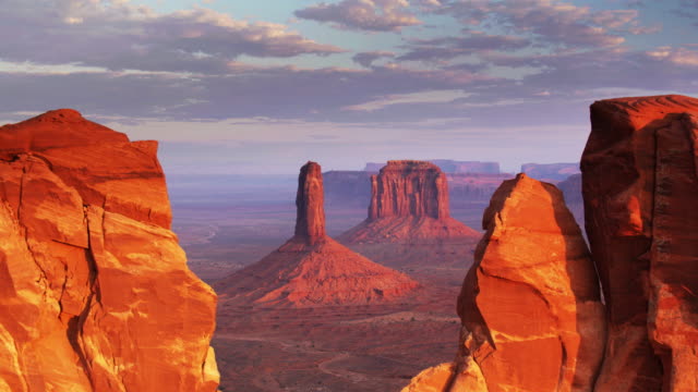 Drone Flight Through Notch in Sandstone Wall Towards Monument Valley Buttes