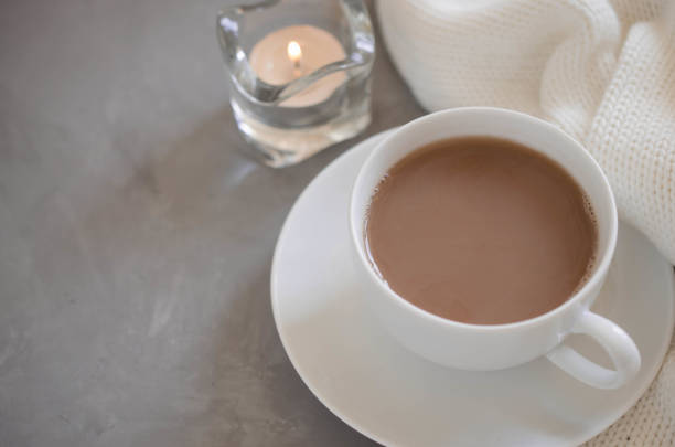 istock Cup of cocoa on a table, candles and knited blanket. 1043709988