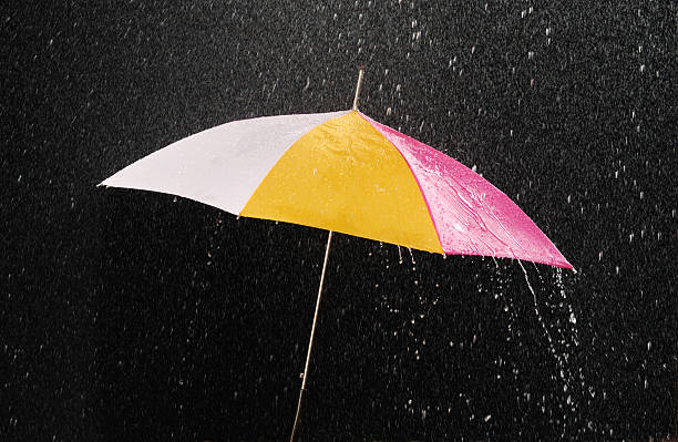 istock White and yellow umbrella, open under the rain, black background 104371385