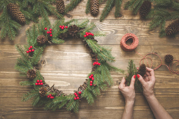 istock Woman making Christmas wreath using fresh and all natural materials. Flat lay. Top view. 1043720962