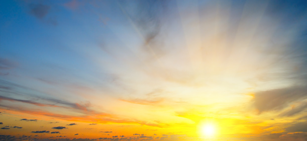 Cloudy sky and bright sun rise over the horizon. Wide photo.