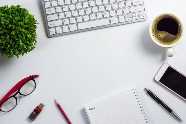 istock Top view, flat design office desk with computer keyboard, coffee cup, smart phone, pen, notebook, pencil, flash drive, glasses and plant pot 1043724954