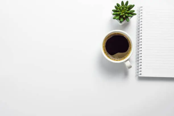 Photo of Office desk with coffee cup, cactus pot and blank notebook
