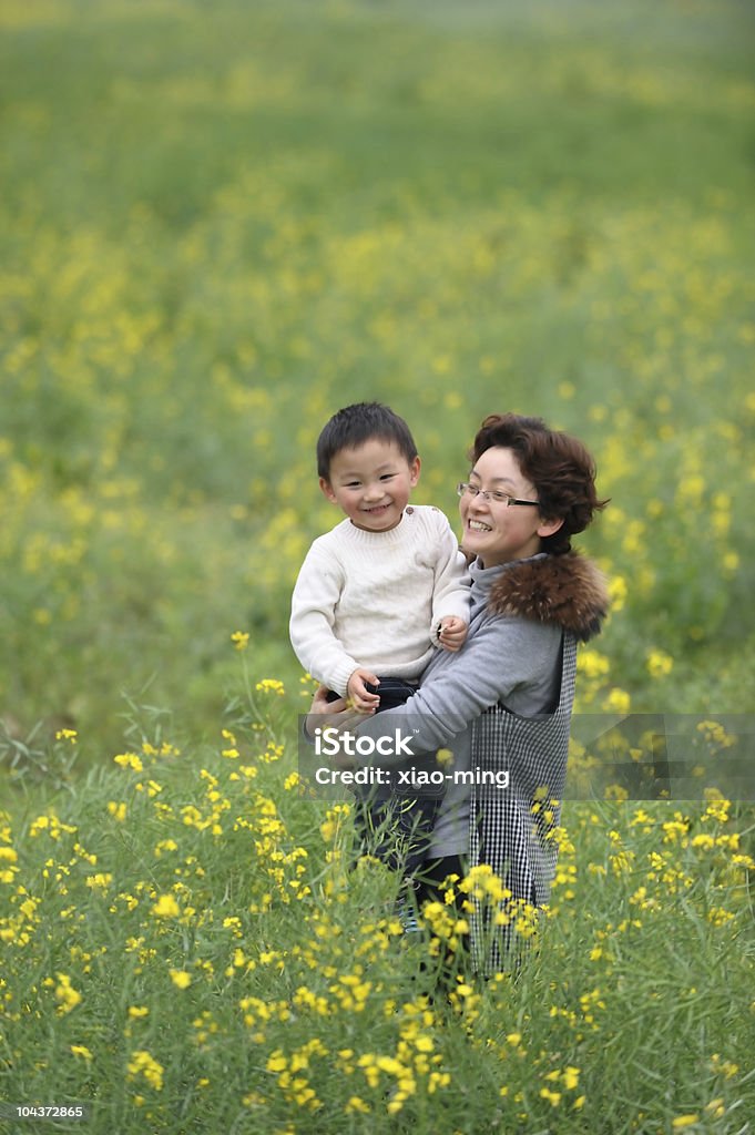 Mãe e filho ao ar livre com flores - Foto de stock de Abraçar royalty-free