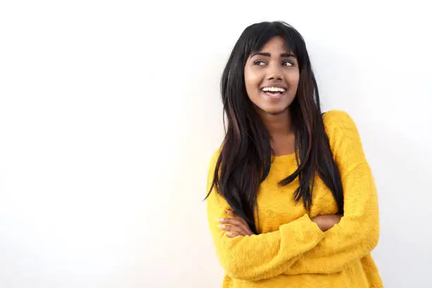 Photo of attractive young Indian woman smiling and glancing at copy space isolated white background