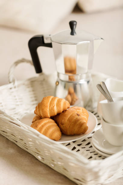 istock Breakfast in bed. On a white wicker tray there is a coffee maker, coffee white cups and croissants. 1043731568