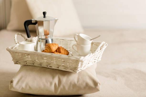 istock Breakfast in bed. On a white wicker tray there is a coffee maker, coffee white cups and croissants. 1043731570