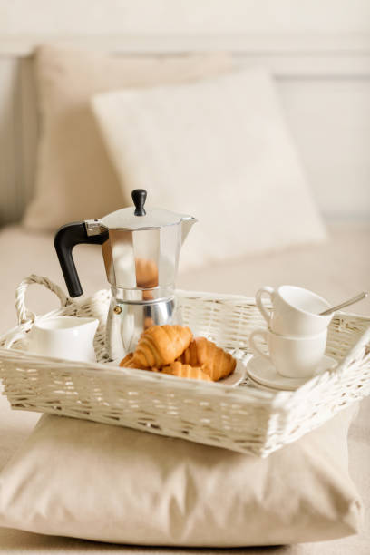 istock Breakfast in bed. On a white wicker tray there is a coffee maker, coffee white cups and croissants. 1043731576