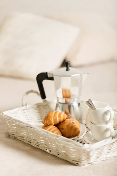 istock Breakfast in bed. On a white wicker tray there is a coffee maker, coffee white cups and croissants. 1043731582