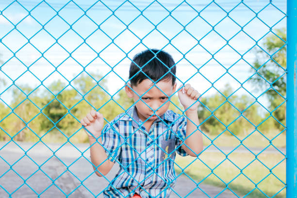 istock The boy stands behind the fence. 1043734164