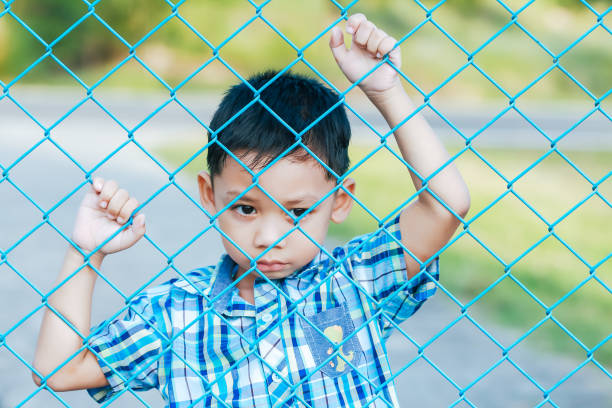 istock The boy stands behind the fence. 1043734186