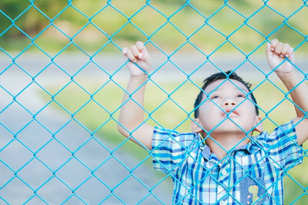 istock The boy stands behind the fence. 1043734204