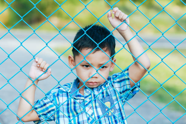 istock The boy stands behind the fence. 1043734228