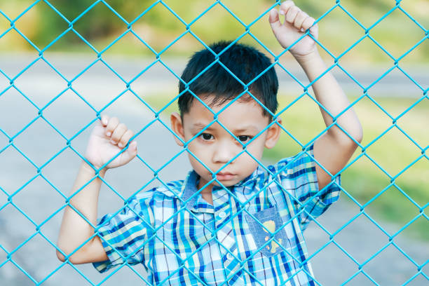 istock The boy stands behind the fence. 1043734236