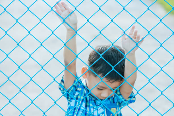 istock The boy stands behind the fence. 1043734242