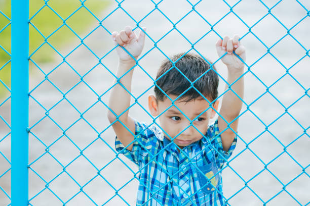 istock The boy stands behind the fence. 1043734252
