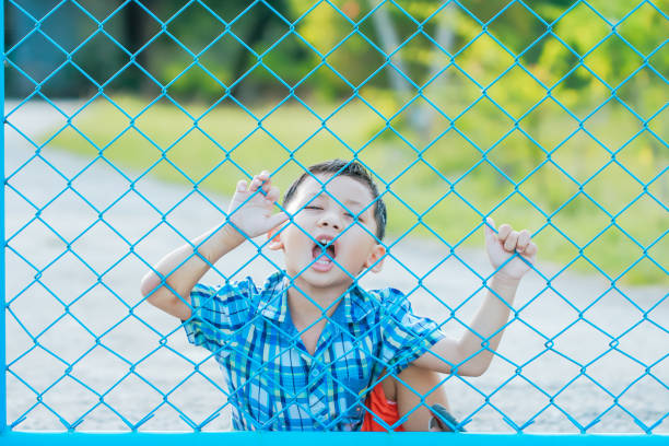 istock The boy stands behind the fence. 1043734286