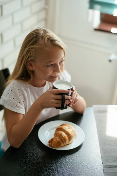 istock Young girl having croissaint and milk 1043734734