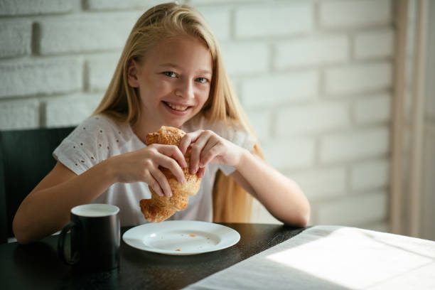 Young girl having croissaint and milk