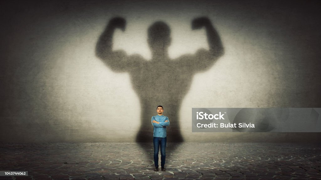 Inner strength Confident businessman imagine himself a powerful hero, casting shadow of big strong muscular bodybuilder showing his biceps. Inner strength, leadership qualities. Business development. Strength Stock Photo