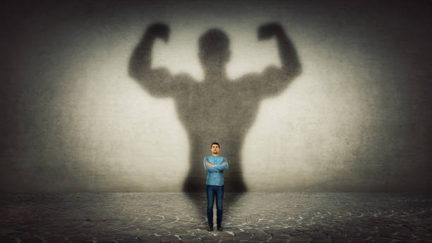 Inner strength Confident businessman imagine himself a powerful hero, casting shadow of big strong muscular bodybuilder showing his biceps. Inner strength, leadership qualities. Business development. braveheart stock pictures, royalty-free photos & images