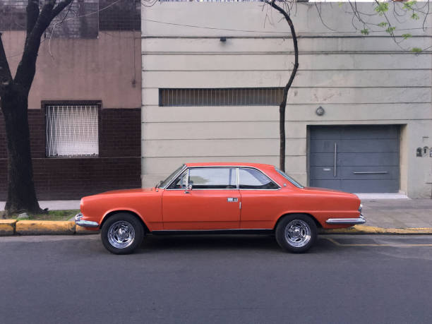 coche vintage naranja aparcado en la calle - inmóvil fotografías e imágenes de stock