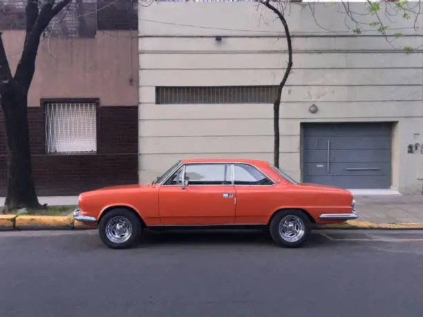 Photo of Orange vintage car parked in the street