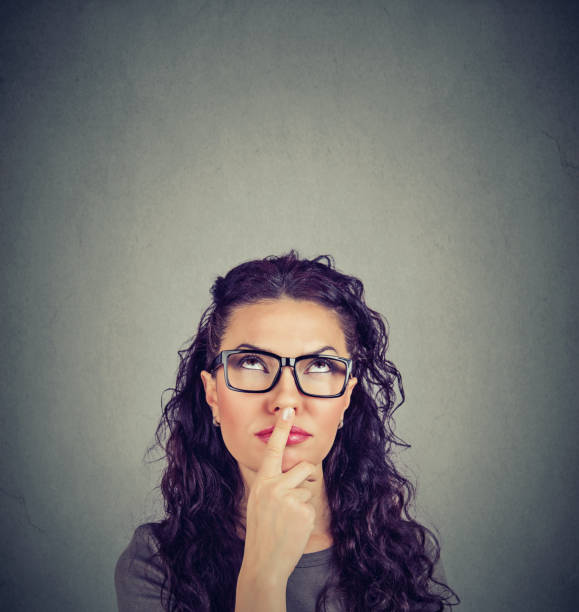 istock Thinking woman touching lips and looking up 1043756324