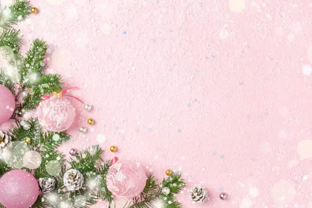 Photo of Christmas frame of New Year ornaments and snow on pink background.