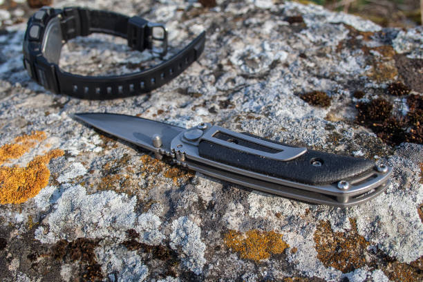 Folding knife and men's watch on stone