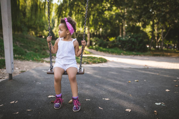 istock Lovely serene child sitting on a swing at a park 1043778662