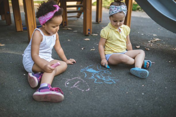 istock Lovely mixed race siblings drawing at a park with chalk 1043778974