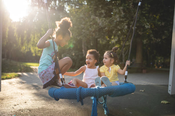 istock Cute siblings having fun together on a park swing 1043785618