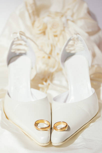 anéis de casamento e sapatos femininos com um vestido no fundo - couple gold pair vertical - fotografias e filmes do acervo