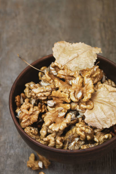 istock Walnuts kernels in a clay bowl on wooden background. 1043795886