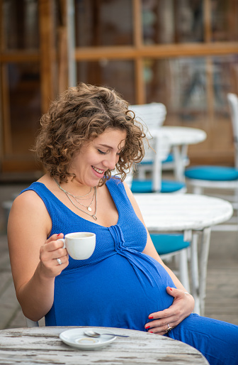 Young pregnant woman enjoying a cup of coffee in cafe